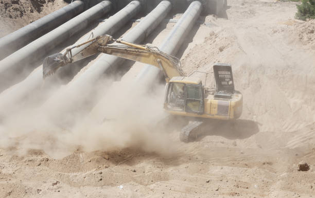 Excavator digging sand on a construction site in a harsh conditions on a hot sunny day.